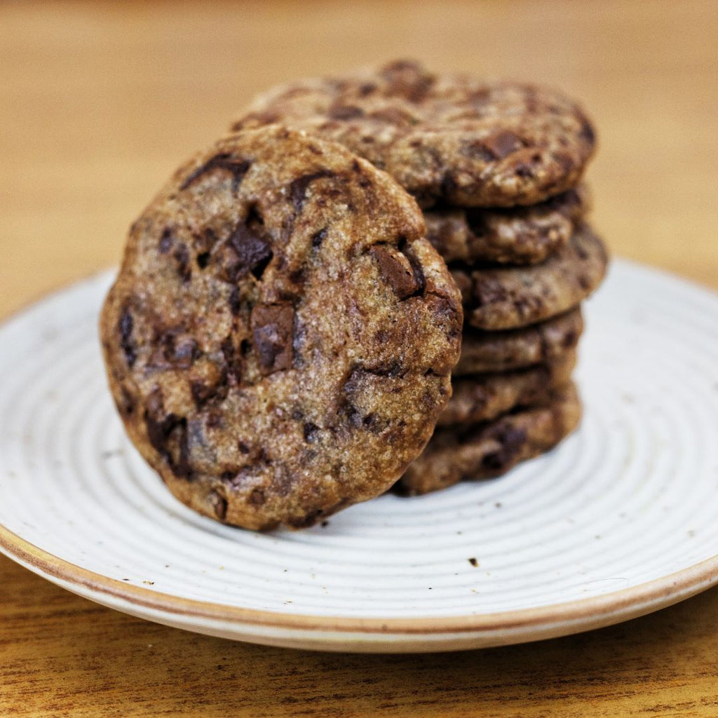 Stack of chocolate chip Kookies on a white plate with a wooden background