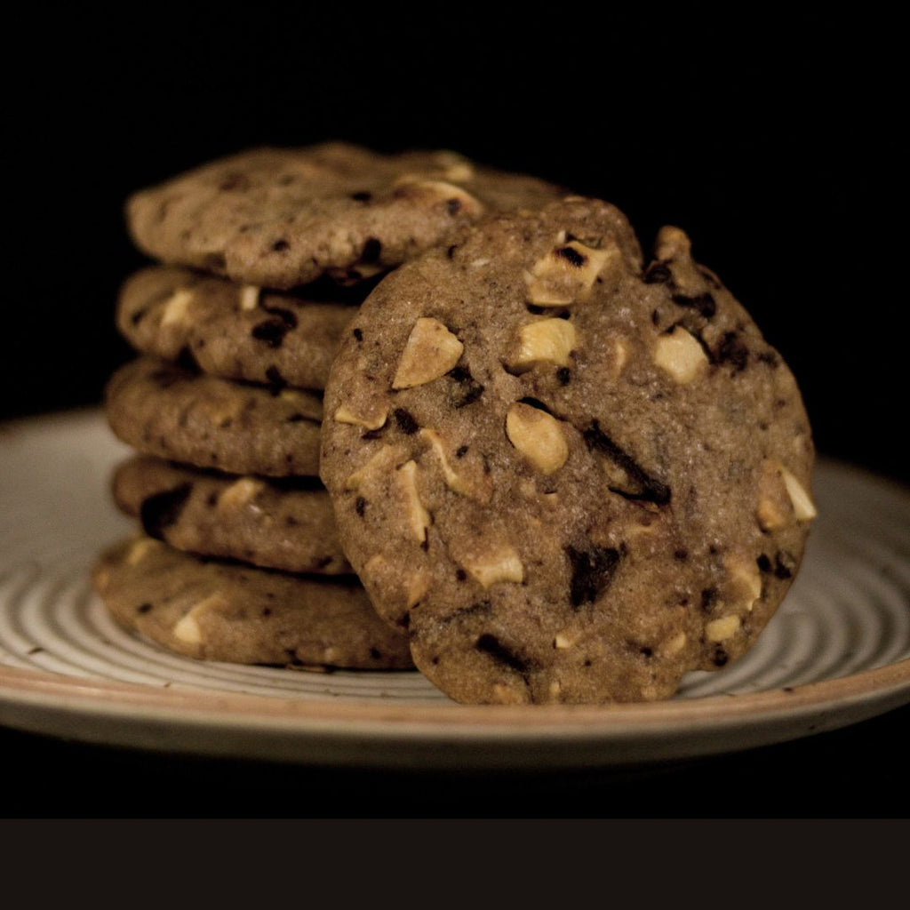 Stack of white and dark chocolate chip Kookies on a plate against a dark background.