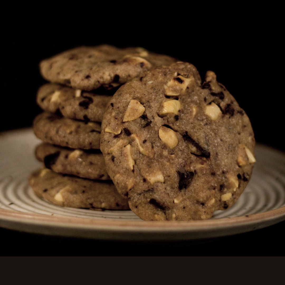 Stack of white and dark chocolate chip Kookies on a plate against a dark background.